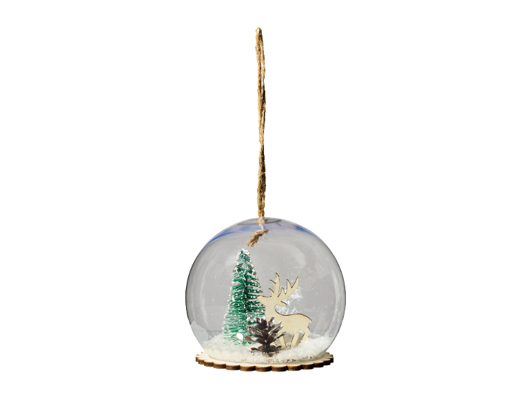 Christmas bauble with snow, tree, deer, and pine cone on a black background.