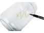 Gold marker drawing a wavy line on a clear glass jar