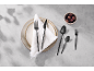 Black cutlery set on a plate with a white napkin and a bowl of olives.