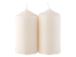 Two cream-colored cylindrical candles with wicks, set against a black background.