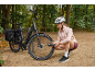 Woman in helmet and pink jacket inflating tire of black e-bike with panniers in a park.