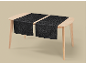 Two black table runners with a floral pattern on a light wooden table.