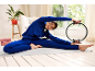 Woman in a blue tracksuit doing Pilates with a Pilates ring on a mat.