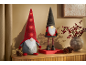 Two festive gnomes with lights and red berries on a wooden table.
