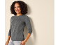 Smiling woman in a gray long-sleeve shirt and light jeans.