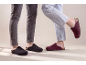 Two pairs of feet in felt slippers, one dark grey and one burgundy.