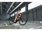 Man on black electric bicycle in a modern warehouse with floor markings.