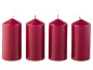 Four red cylindrical candles with white wicks on a black background.