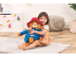 Little girl hugging a large plush bear, sitting on a light rug.
