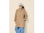 Woman in a beige parka, light grey beanie, and jeans.
