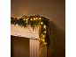 Christmas garland illuminated with warm lights on a white fireplace.