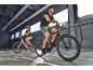 Two people riding electric bikes in an indoor setting.
