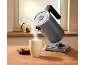 Electric kettle pouring hot water into a mug, with cookies and a teapot.