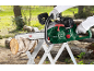 Green chainsaw cutting a log on a sawhorse in an outdoor setting.