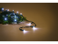 White LED Christmas lights on a green pine branch, on a warm brown background.