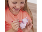 A child coloring a small pink pig toy with a felt-tip pen.