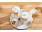 Two glasses of layered latte macchiato with foamed milk, amaretti biscuits, and a spoon.