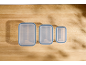 Three rectangular Silvercrest food containers with blue lids on a wooden table.