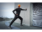 Man in black activewear and orange beanie with headlamp stretching outdoors.