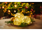 Glowing Christmas baubles on a tray with fir branches in front of a tree