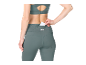Woman in green leggings and sports bra, putting a card into the back pocket.