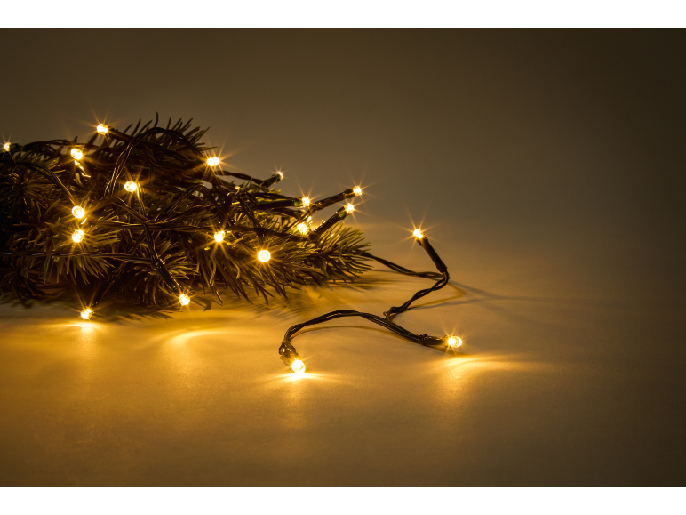 Warm Christmas lights on pine branches, creating a festive ambiance.