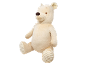 Cream-colored plush teddy bear with a brown nose, sitting and looking to the side