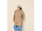 Woman in a beige coat, blue jeans, and a grey beanie