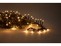 Christmas string lights with warm white LED bulbs and green pine needles.