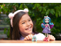 Smiling girl with a doll and a small toy on a wooden surface.