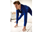 Man in blue tracksuit stretching on a white floor.