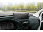 Black car dashboard pillow for moisture absorption, placed on the car's dashboard.