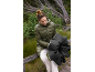 Woman in olive green puffer jacket and white trousers holding a black umbrella.