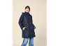 Woman in navy hooded rain jacket and jeans, smiling.