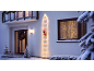 House decorated with Christmas lights, a ladder with Santa, and a wreath on the door.