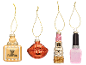 Four festive ornaments shaped as perfume, lips, lipstick, and nail polish.