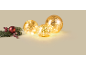 Christmas decorations: three golden glowing orbs and a sprig with red berries.
