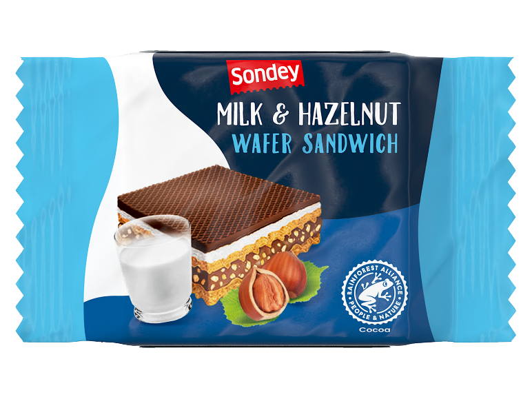 Milk & hazelnut wafer sandwich with a chocolate layer, accompanied by a glass of milk and hazelnuts.