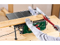 Table saw cutting a wooden board, with a gloved hand and push stick.