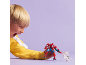 A boy plays with a red and blue superhero action figure and a white figure.