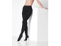 Woman in black opaque tights, leaning on a white block.
