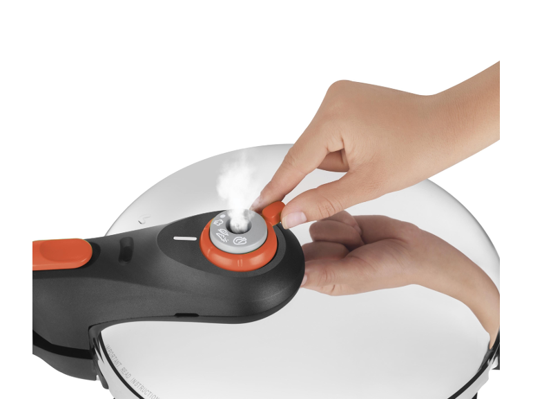 Hand adjusting the valve of a pressure cooker with steam escaping.