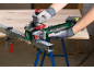 Angle grinder cutting a metal profile clamped with a G-clamp on a workbench.