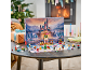 Children's advent calendar with a toy castle and figures on a table in front of a fireplace.