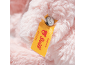 Yellow tag with red text and a metal button on a pink plush toy.