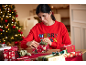 Woman in a red Christmas jumper with 'MERRY XMAS' text wrapping gifts.