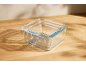 Set of three glass food storage containers on a wooden surface.