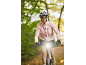 Woman on a bike with a helmet and sunglasses, the bike's front light is on.