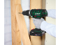 Person's hand using a cordless drill to screw a screw into a wooden board.