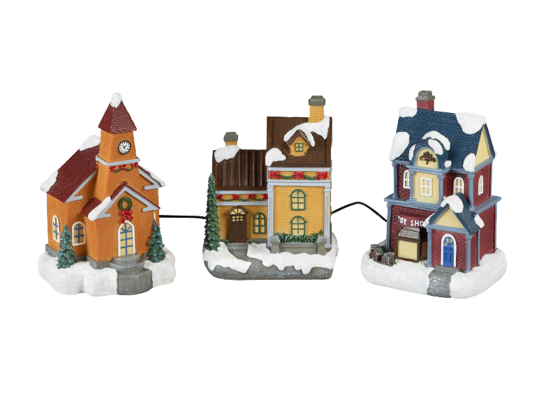 Three festive Christmas village houses with snow-covered roofs, including a church and a toy shop.